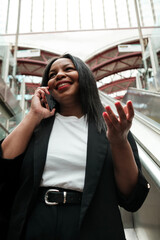 Businesswoman talking on phone while ascending escalator in station