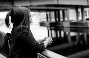 Businesswoman leaning on railing contemplating by water in monochrome analog style
