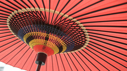 Close-up view of the underside of a vibrant red traditional Japanese umbrella showcasing intricate geometric patterns and a wooden handle