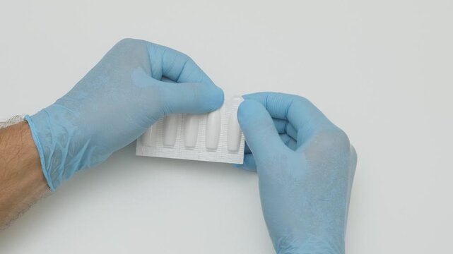 doctor in blue gloves separates medical candle from blister, slow motion
