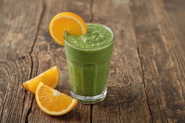 Smoothie made from fresh spinach and oranges on a wooden surface