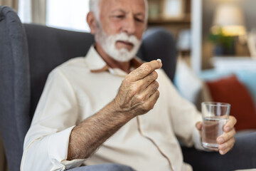Shot of an elderly man taking his medication at home.