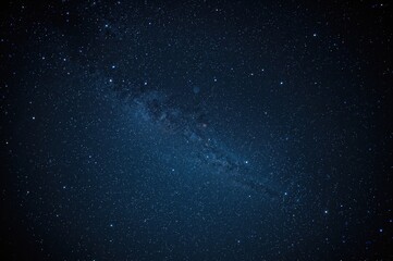 The dark sky is cloud-covered with faint stars and a blurred Milky Way visible against a deep blue backdrop. Cosmic noise and hazy galaxies fill the scene, captured using a long exposure.