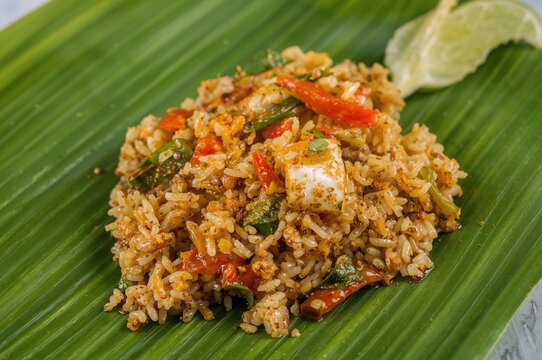 Close-up of a vibrant spicy rice salad featuring vegetables and fermented fish sauce served on a banana leaf, showcasing a traditional healthy homemade dish