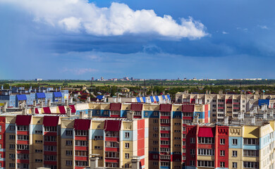 Colorful houses, a plain and a city in the distance under a cloudy sky