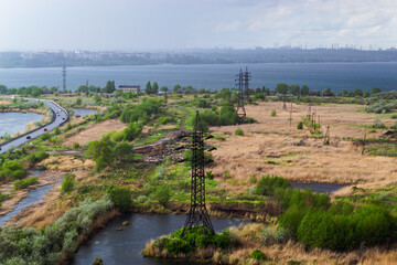 Heavy rain over the city and factories behind power lines in the field