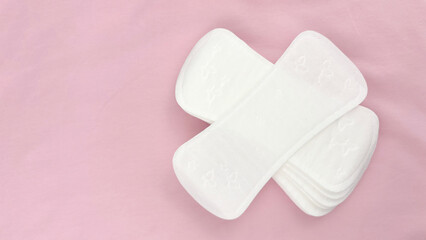 Women's sanitary pads on pink background, top view. Feminine hygiene and menstruation product. Daily pad for period care, women's health, advertising, article or banner concept, copy space