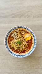Bowl of Hot Instant Noodles Served with Boiled Egg, Vegetables and Crackers