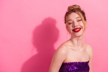 Young woman with glamorous style and red lipstick posing against a pink background wearing a shiny...