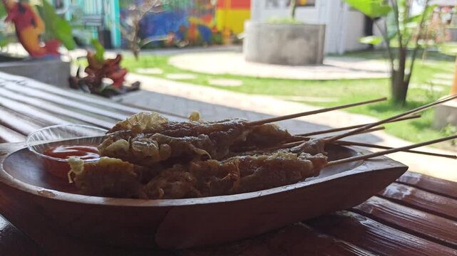 Traditional Indonesian street food called Sempol, made from seasoned chicken or fish, skewered and fried, served with spicy sauce.