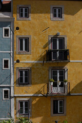 Obraz premium Lisbon, Portugal - Yellow building with a balcony and a blue and white building in the background. The yellow building has a lot of windows and a balcony