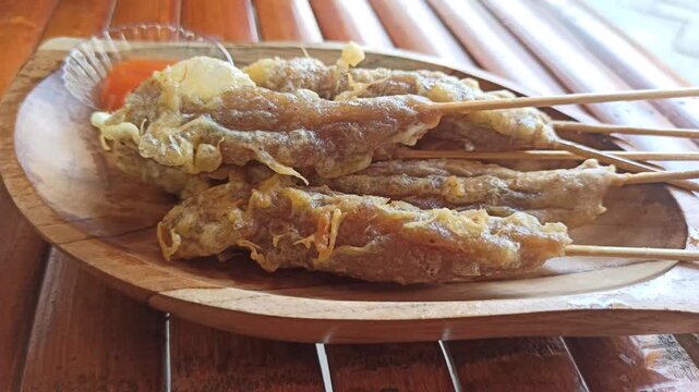 Traditional Indonesian street food called Sempol, made from seasoned chicken or fish, skewered and fried, served with spicy sauce.