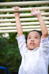 Obraz premium Portrait of Happy child girl play at monkey bar, energy or exercise at park. Exercise for health of 8-9 year old Asian girls. Vertical image.