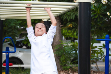 Fototapeta premium Happy Asian child on monkey bars. Kid girl at school playground. Sweet smile. Children aged 8-9 years old.