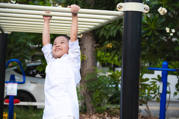 Obraz premium Happy Asian child girl having fun playing on monkey bars in a playground. Kid age 8-9 years.