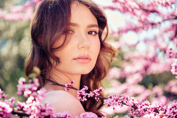 Naklejka premium Young woman in floral spring setting, showcasing natural beauty and relaxed atmosphere outdoors with blooming flowers
