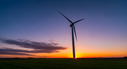 Wind Turbine Spinning in a Vibrant Sunset Sky Over a Green Field