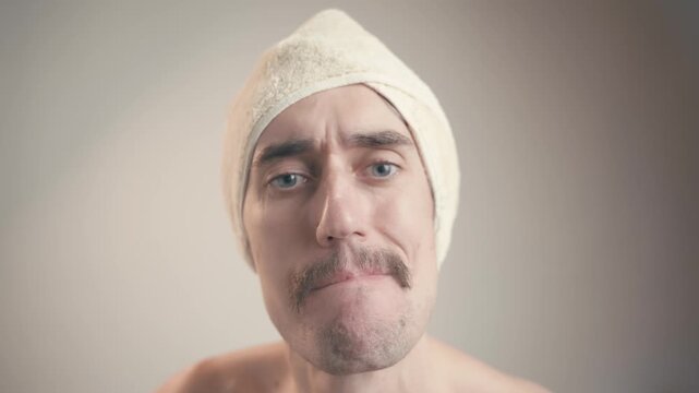 So-so evaluation of a young handsome man with a mustache and towel, showcasing quirky expressions and lively gestures, transitioning from serious to humorous against a soft background.