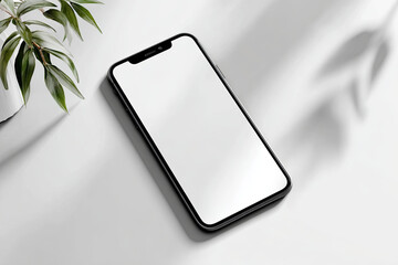 Sleek smartphone displaying blank white screen resting near green houseplant on clean white desk, representing contemporary minimalist workplace design
