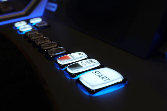 Close-up view of illuminated buttons on a modern slot machine in a casino, glowing in blue light and labeled with betting functions