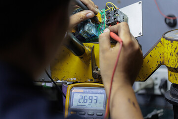 Over the Shoulder View of Technician Using Multimeter on Circuit Board