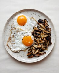 Fried eggs with sautéed shiitake mushrooms on a speckled plate