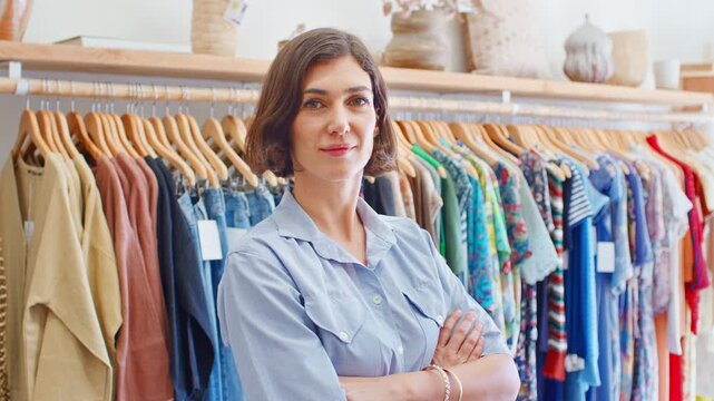 Portrait Of Female Owner Of Fashion Store Standing In Front Of Clothing On Rails