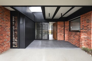Modern residential entrance showcasing a blend of brick and metal design elements in a suburban neighborhood during daylight hours