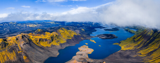 Aerial image of moss covered volcanic ridges, deep blue lakes, dark soil, and craters in Iceland,...