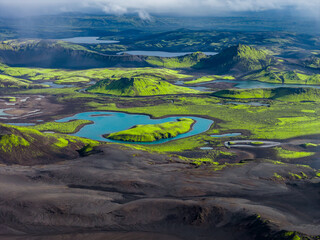 Aerial image of Iceland's volcanic terrain with green moss, craters, lakes, and a heart shaped lake...
