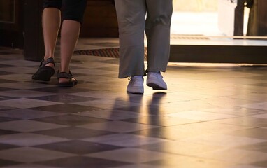 Two people walking indoors on checkered floor with casual footwear