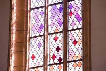 Sunlit stained glass window with colorful geometric patterns in historic building