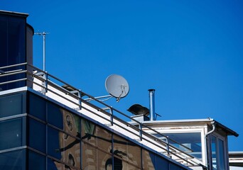 Modern urban rooftop with satellite dish against blue sky