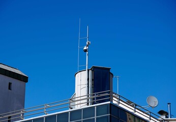 Obraz premium Modern rooftop architecture with satellite dishes and antennas against clear blue sky