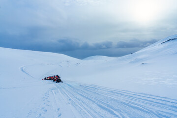 Tourists riding snowmobile on snowy glacier mountain landscape