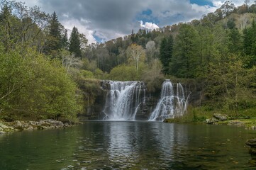 Fototapeta premium Scenic countryside featuring a cascading waterfall amidst lush greenery