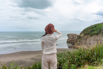 Asian woman enjoying on coastline near Muriwai Gannet Colony in New Zealand