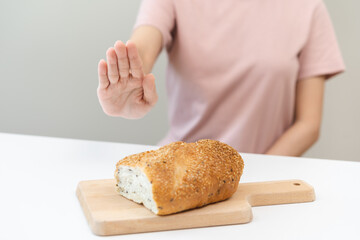 Gluten allergy, asian young woman hand push out, refusing to eat white bread loaf on board in...
