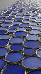 Naklejka premium Repeating pattern of circular blue discs with golden edges, viewed at an angle, creating a textured and dynamic surface