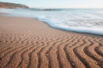 Fototapeta premium Sea-formed sand patterns on a tranquil shoreline, showcasing nature's artistry.