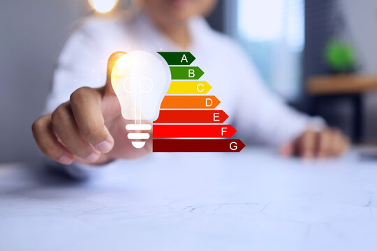 Energy labeling concept with hand pointing on light bulb to define energy efficiency rating to indicate electric power consumption save - Powered by Adobe