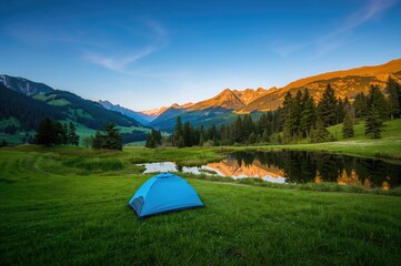 Stunning summertime scenery with a blue tent amidst lush green meadows and mountains at dawn. Nature background