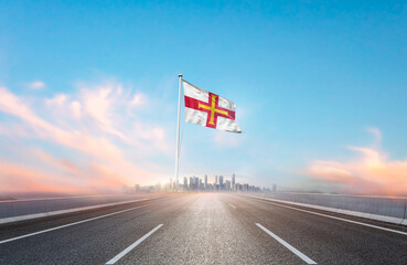 Guernsey national flag with mast waving with beautiful skyline. A view from highway. Guernsey...