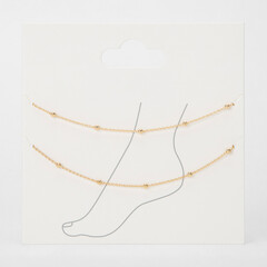 Delicate gold beaded anklets two pack on retail card with foot outline
