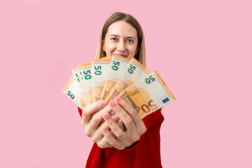 Happy woman showing fan of euro banknotes on pink background. Concept of financial success, income...