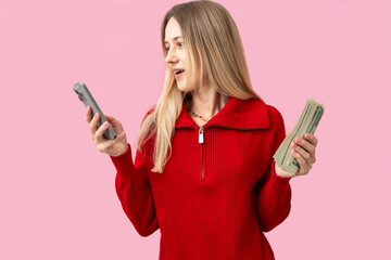 Excited woman with smartphone and cash dollars in hands on pink background. Concept of online...
