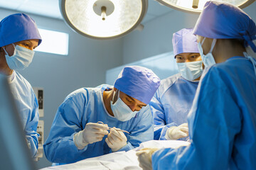 A group of surgeons are performing a surgery on a patient. Scene is serious and focused, as the...