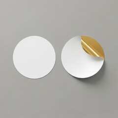 Two white circular stickers one peeled back showing gold foil