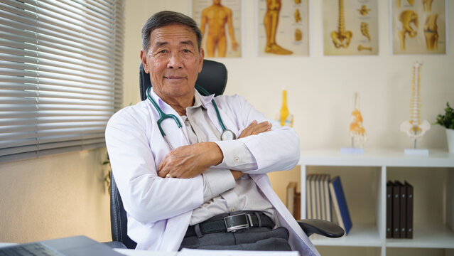 Portrait of a confident senior male doctor sitting in his office with arms crossed, conveying trust and professionalism.