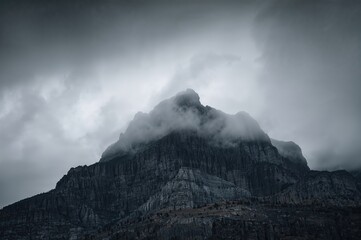 A rugged mountain face under heavy gray clouds sets a moody scene.